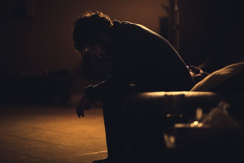 A person sitting hunched over in a chair, appearing dejected.