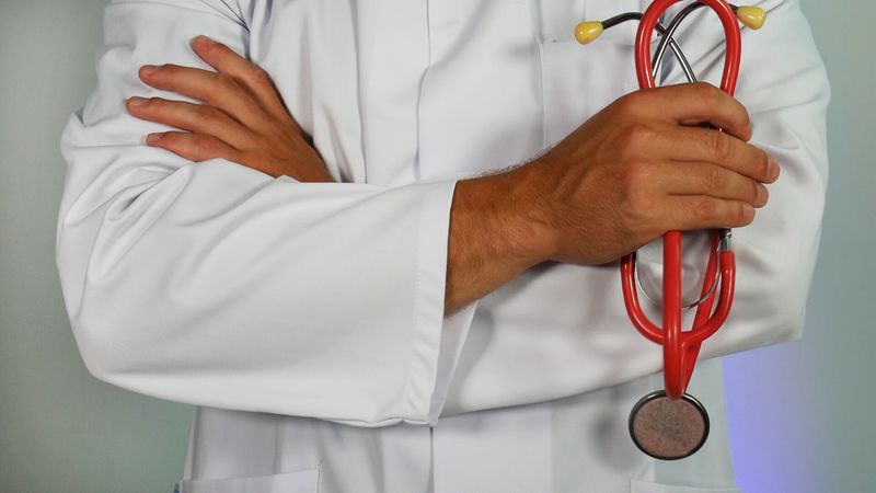 A doctor holding a stethoscope with folded arms.