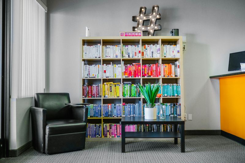 A room with a large bookshelf containing many books.