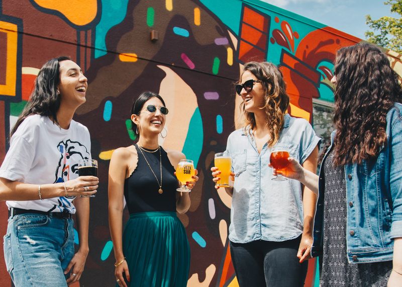 Four women smiling and holding drinks