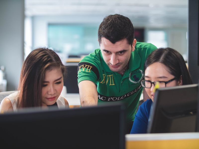 Teacher explaining an activity to two students using computers