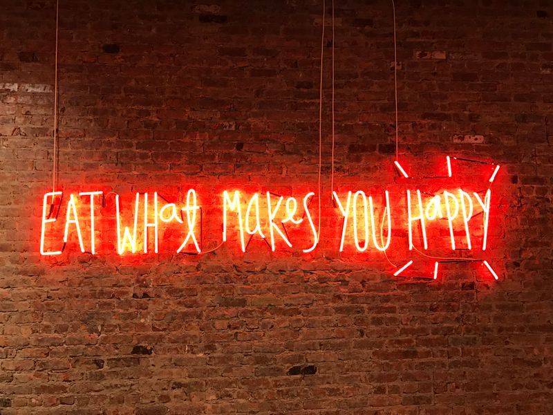 Image of neon sign with text 'Eat what makes you happy'.