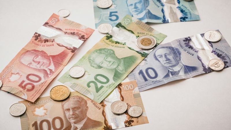 A series of Canadian dollar bills and coins on a table.