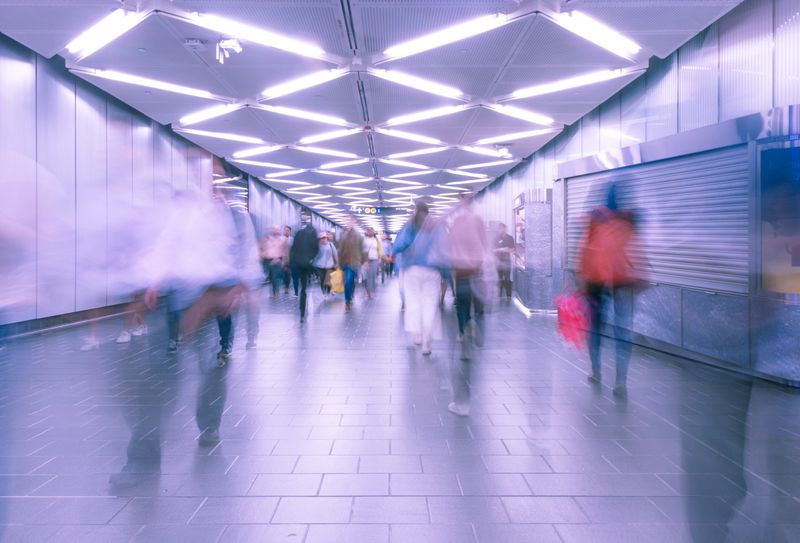 People walking quickly though a transit system hallway.