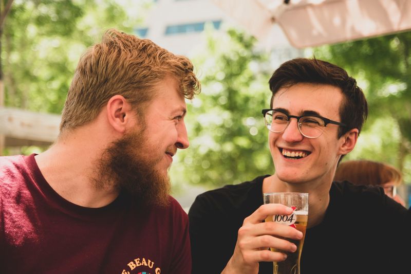 Two friends enjoying a drink together on a patio.