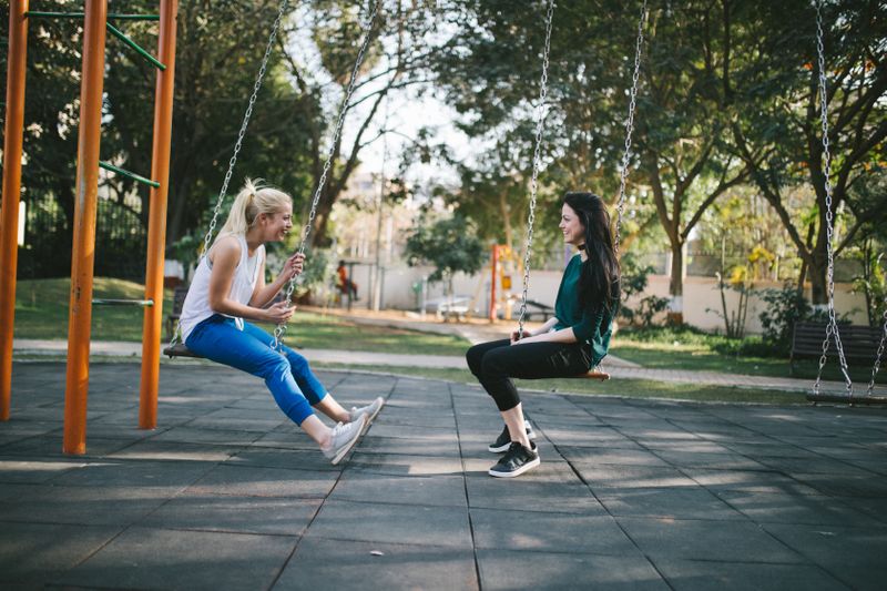 Two girls on a swing talking