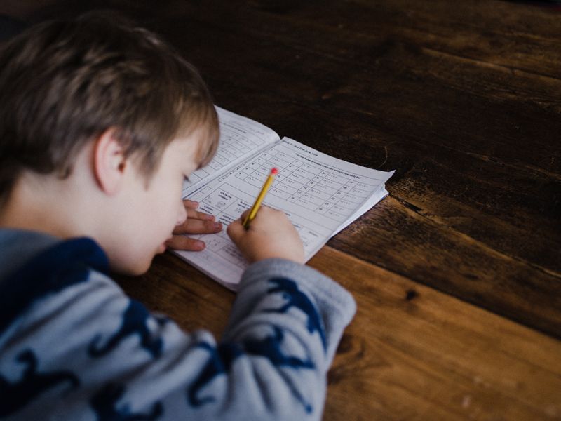 A boy writing notes in a notebook.