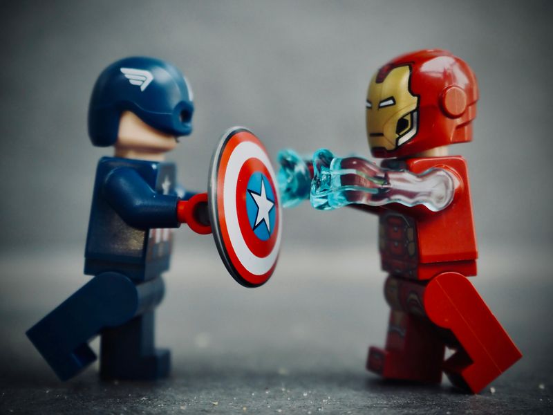 Two Lego figures from the Marvel universe, Captain America and The Flash, fighting each other.