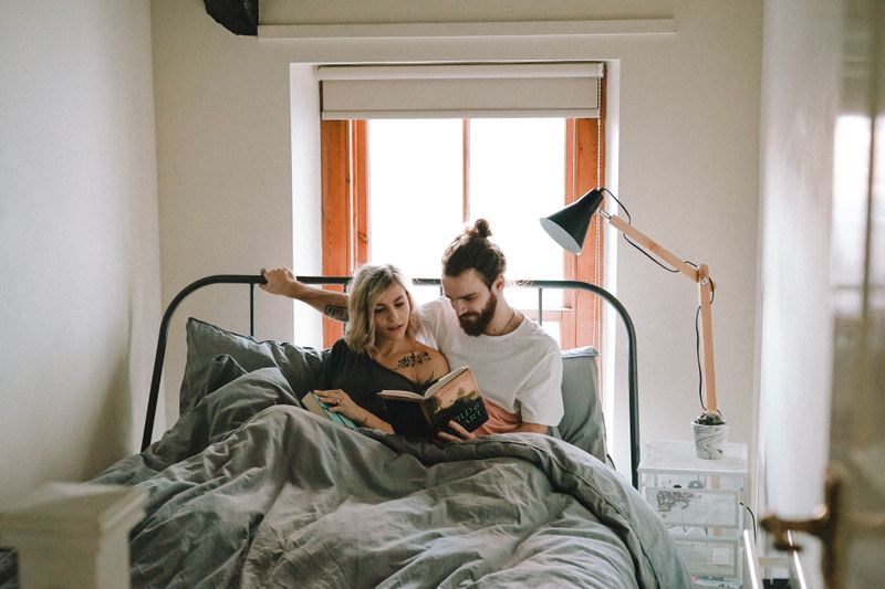 A couple in bed, male is holding a book