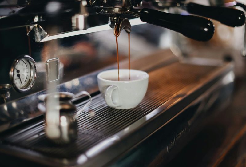 An espresso machine filling up a small coffee cup.