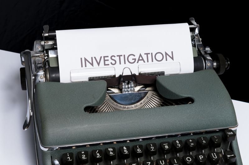 typewriter with a piece of paper that says "INVESTIGATION"