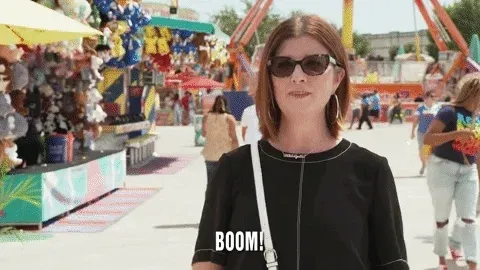 Job interview zoom background. A woman pointing at herself and saying, 'Boom!' There's a carnival in the background.