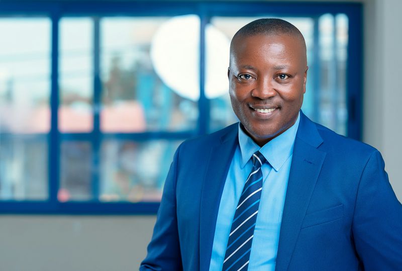 A smiling office worker wearing a blue suit and tie.