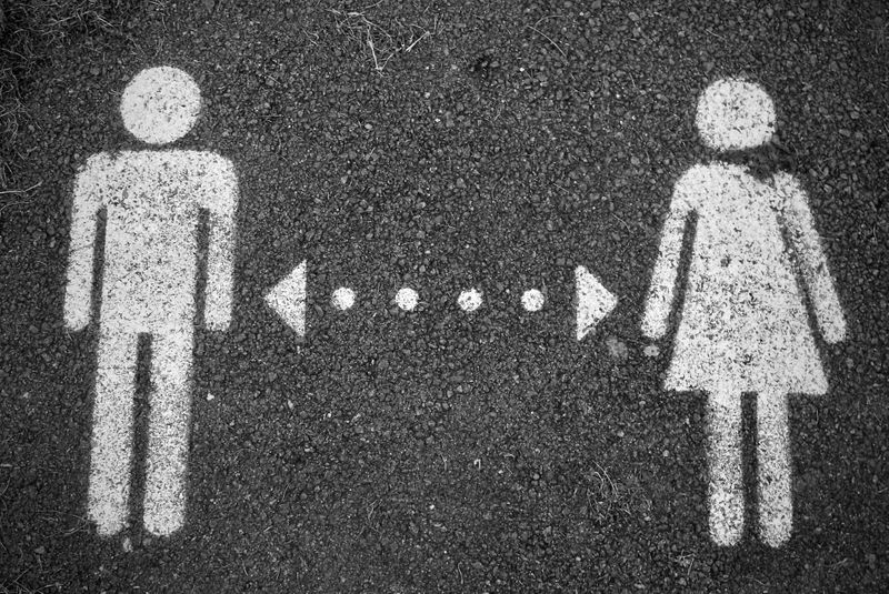 A symbol painted on pavement of a man and a woman, in between them there is a line with arrows on both ends.