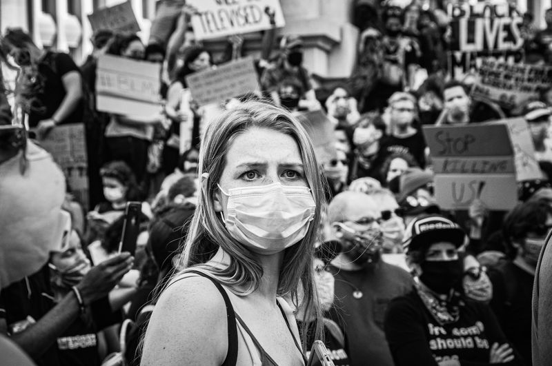 Image: person with mask looks ahead in the middle of a protest