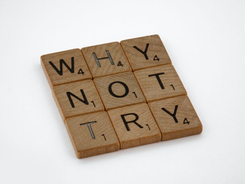 Scrabble tiles spell the words 'Why,' 'not,' and 'try'