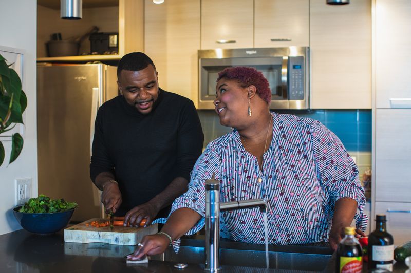 A couple in a kitchen preparing food and discussing their future.