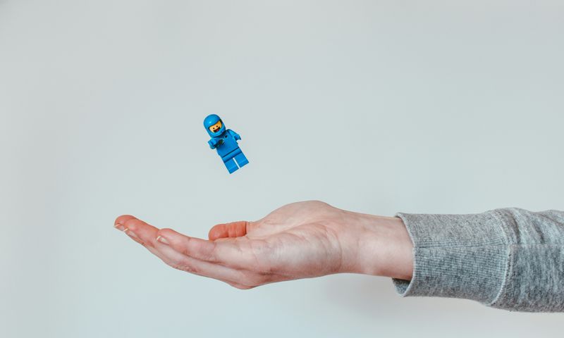 A hand catching a Lego minifigure in a space suit.