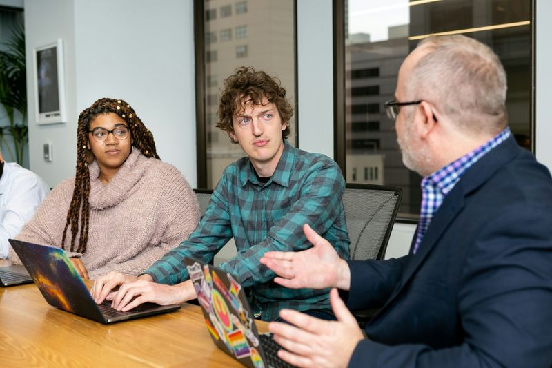 A higher ed professonial speaking to two students.