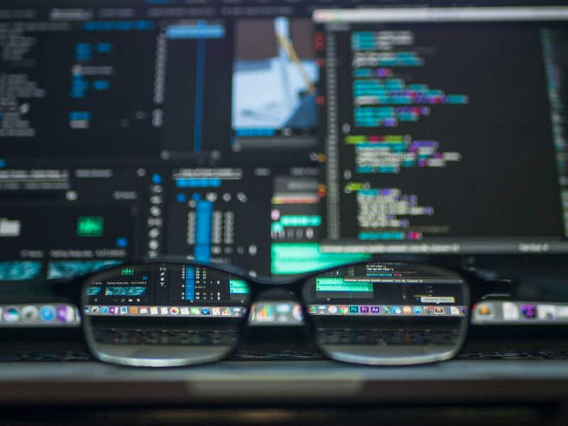 A pair of glasses sit on a laptop. Code on the screen is out of focus, except for through the lenses of the glasses. 