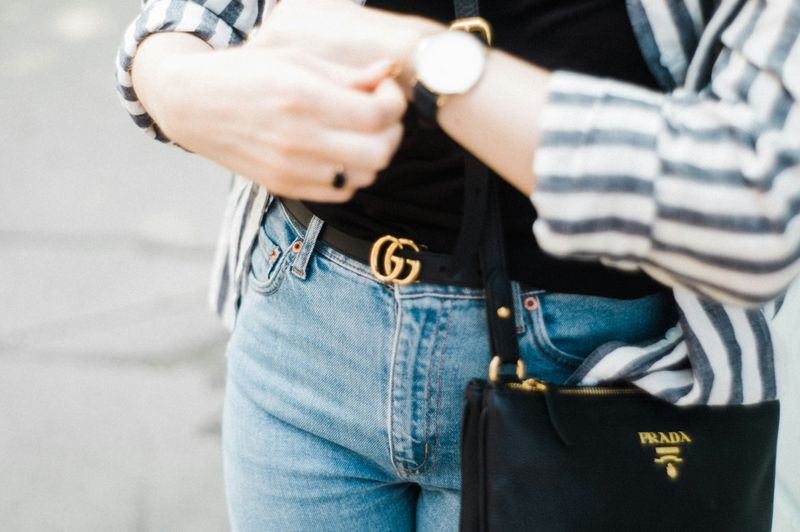 A woman wearing a brand name purse, belt, and watch.