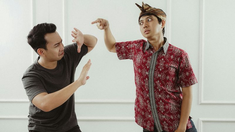 Two men face away from each other with tense expressions, suggesting a moment of conflict or unresolved anger in their relati