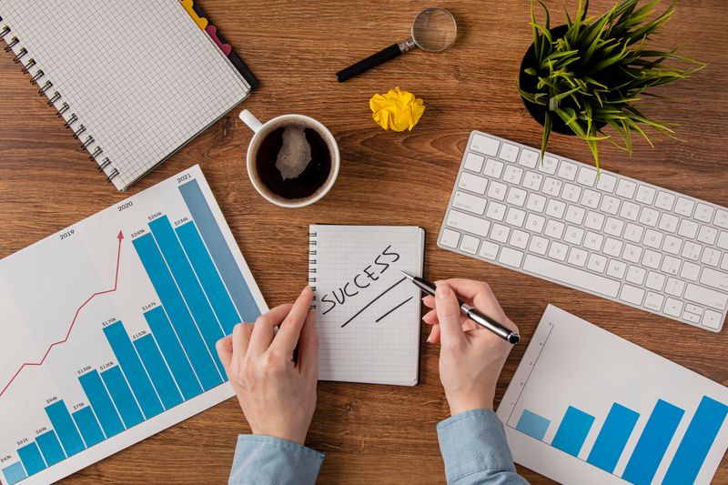 An office desk with a growth chart on it. A person writes 