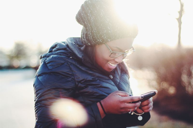 a women smiling at her phone while texting