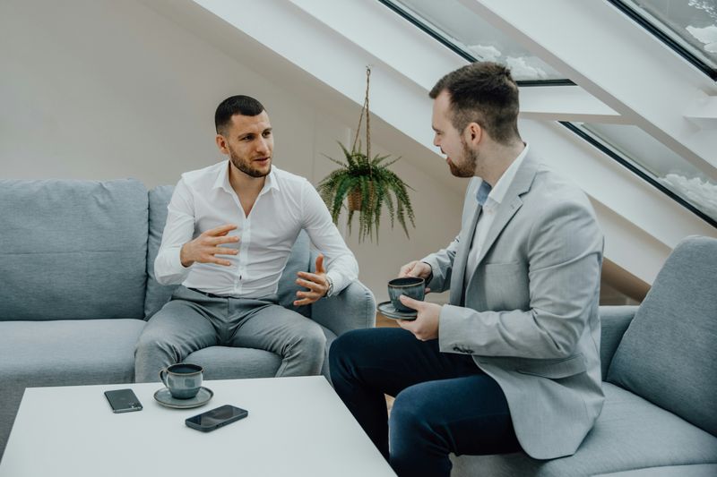 Two coworkers sitting around a table talking.
