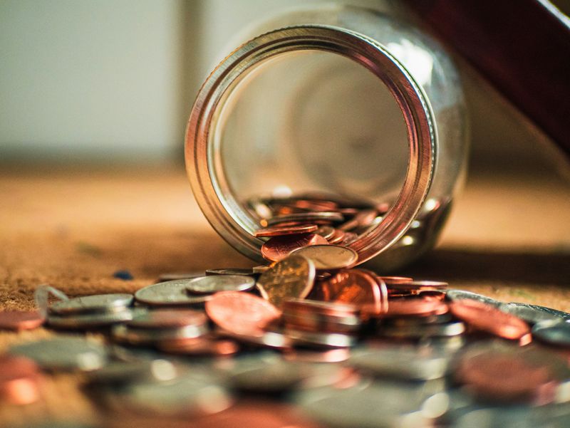 Coins spilling out of a glass jar.