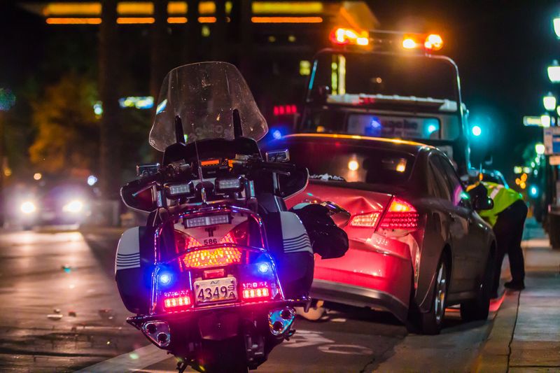 A police motorcycle and tow truck at a nighttime car accident scene.