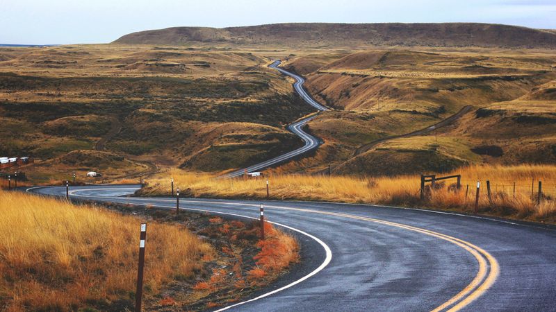 Winding road through hills bordered by grasslands