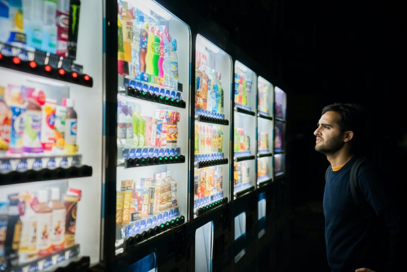 A man choosing between many drinks at a drink machine.