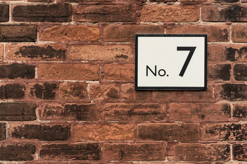 A brick wall with the number 7 on a sign.