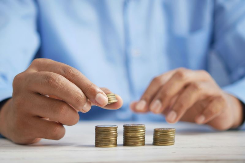 A pair of hands placing coins into a pile.