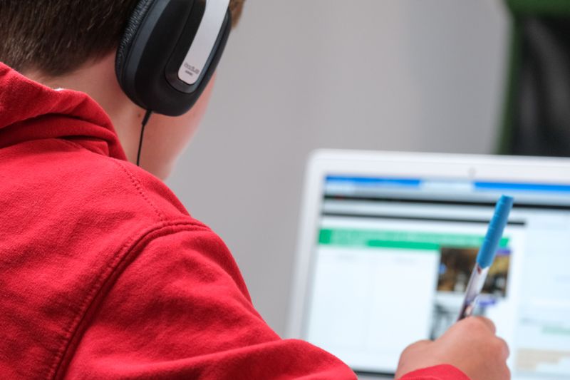 College Student wearing headphones studying on computer.