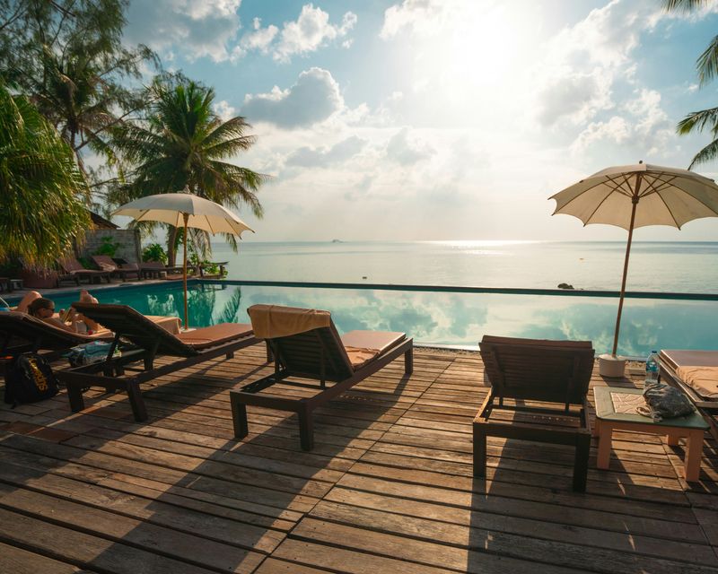 A scenic view of a luxury hotel beach with rows of empty chairs arranged neatly on the sand.