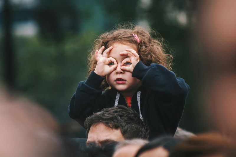 A young girl pretends her hands are binoculars.