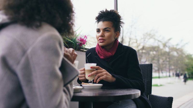 Two women meet and have a serious discussion on a coffee shop patio.