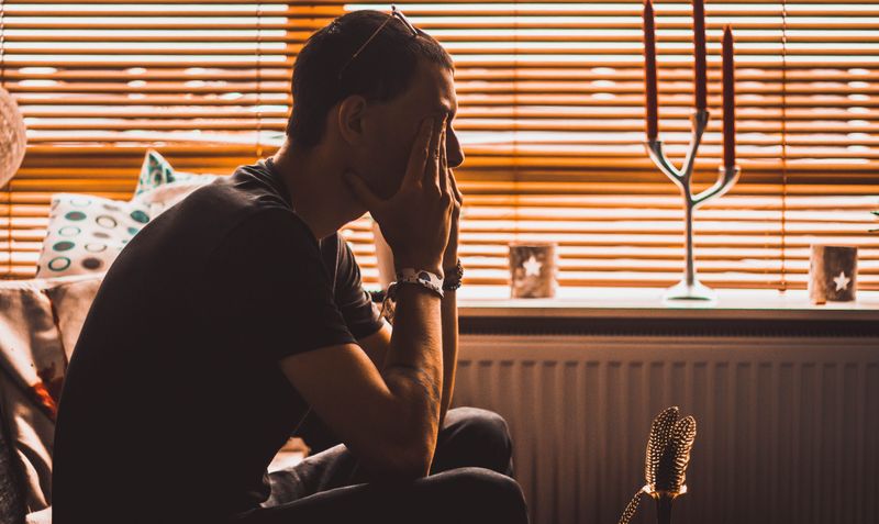 A man putting his hands over his face, looking sad.