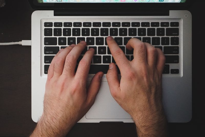 Hands typing on a laptop