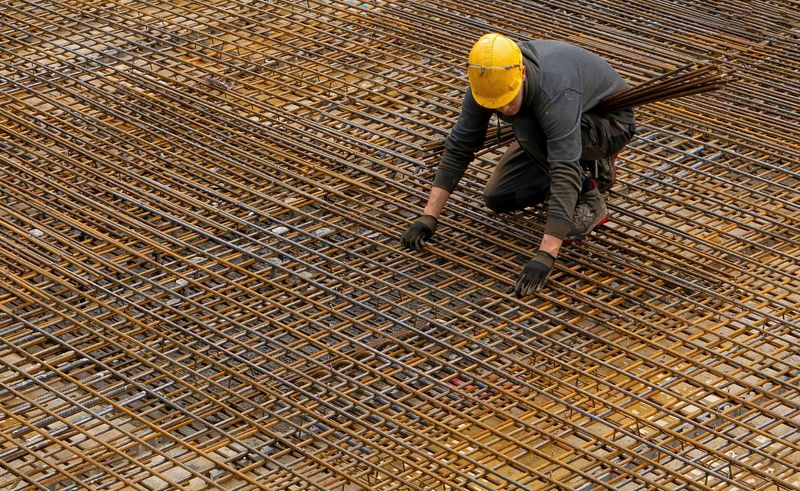 Construction worker laying rebar for concrete foundation.