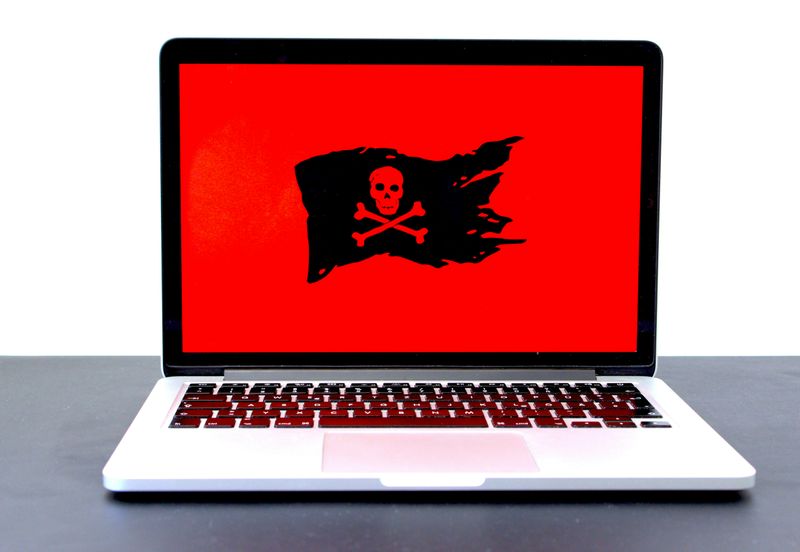 A laptop with a red screen and pirate flag on it with a skull and two crossed bones.