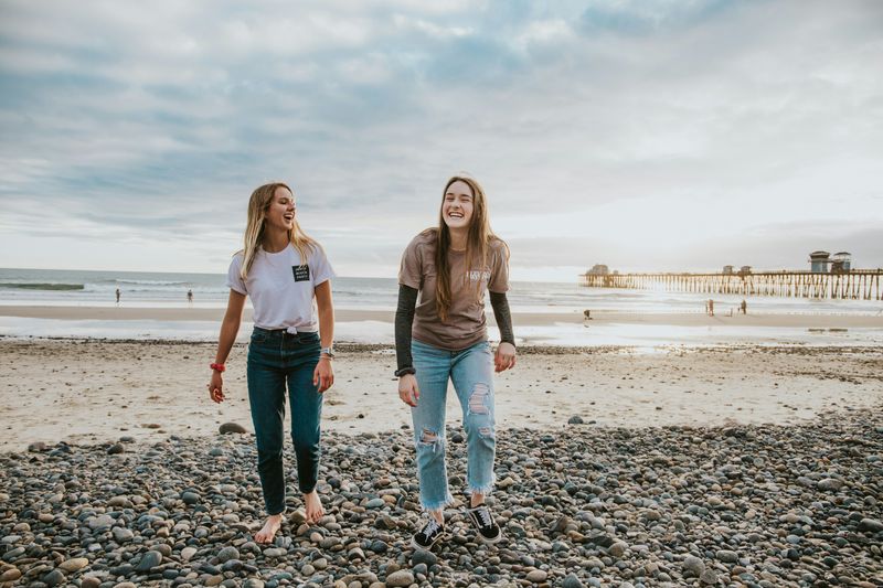 Two girls walking along a beach.