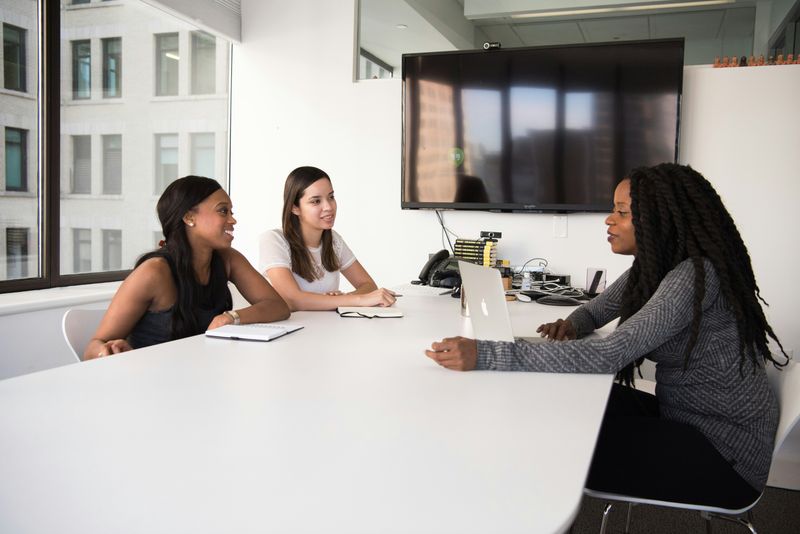 Two human resources professionals are engaged in a conversation with a job candidate during an interview session.