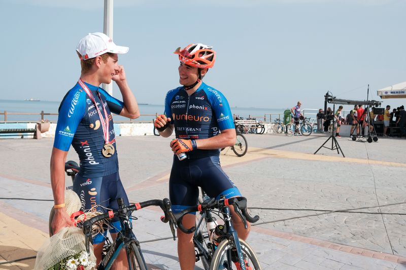 Two cyclists talking to each other on a beach boardwalk.