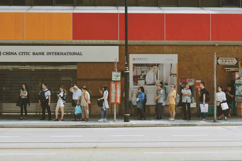 People waiting at a bus stop with no shelter.