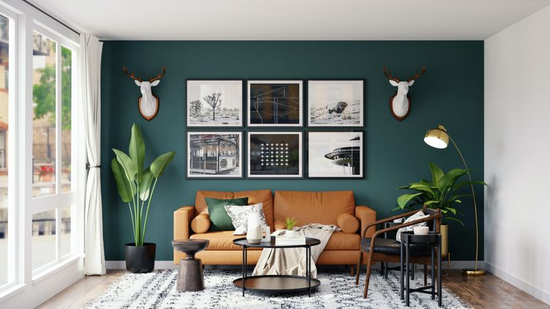 A sitting room with various home decor items such as plants, pictures, lighting, and a rug framing the orange couch.