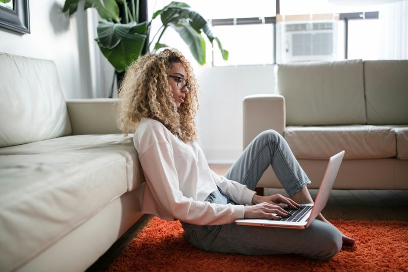 A woman typing on her laptop in her living room.