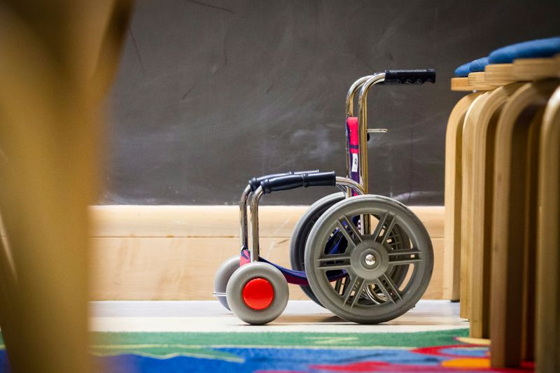 A wheelchair parked next to a line of stools.